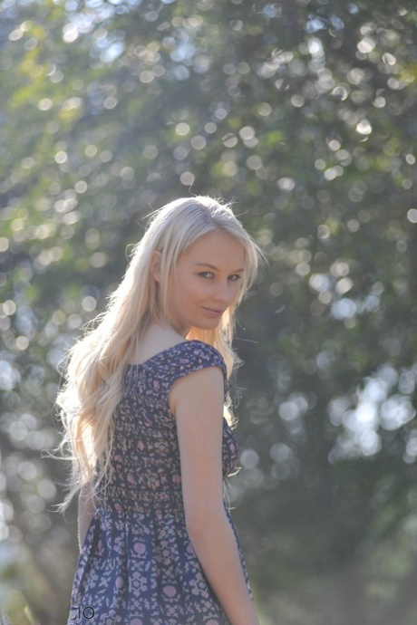 Blonde girl feels the warmth of nature on her naked body in a country setting 85044098
