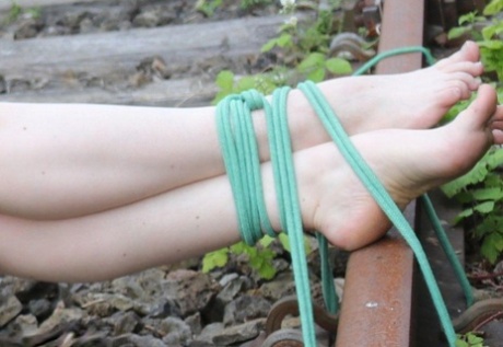 Natural redhead is tied to a train tracks while wearing a dress and glasses 28197472